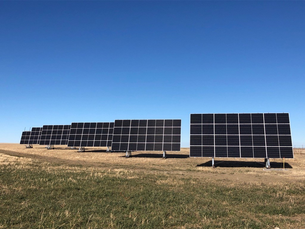 A farmers field with azgard's solar systems with the sun shining down